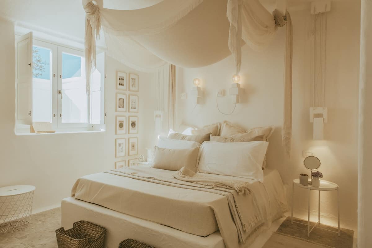 Ein Schlafzimmer mit Himmelbett, Nachttischen und einem Fenster mit Vorhängen.