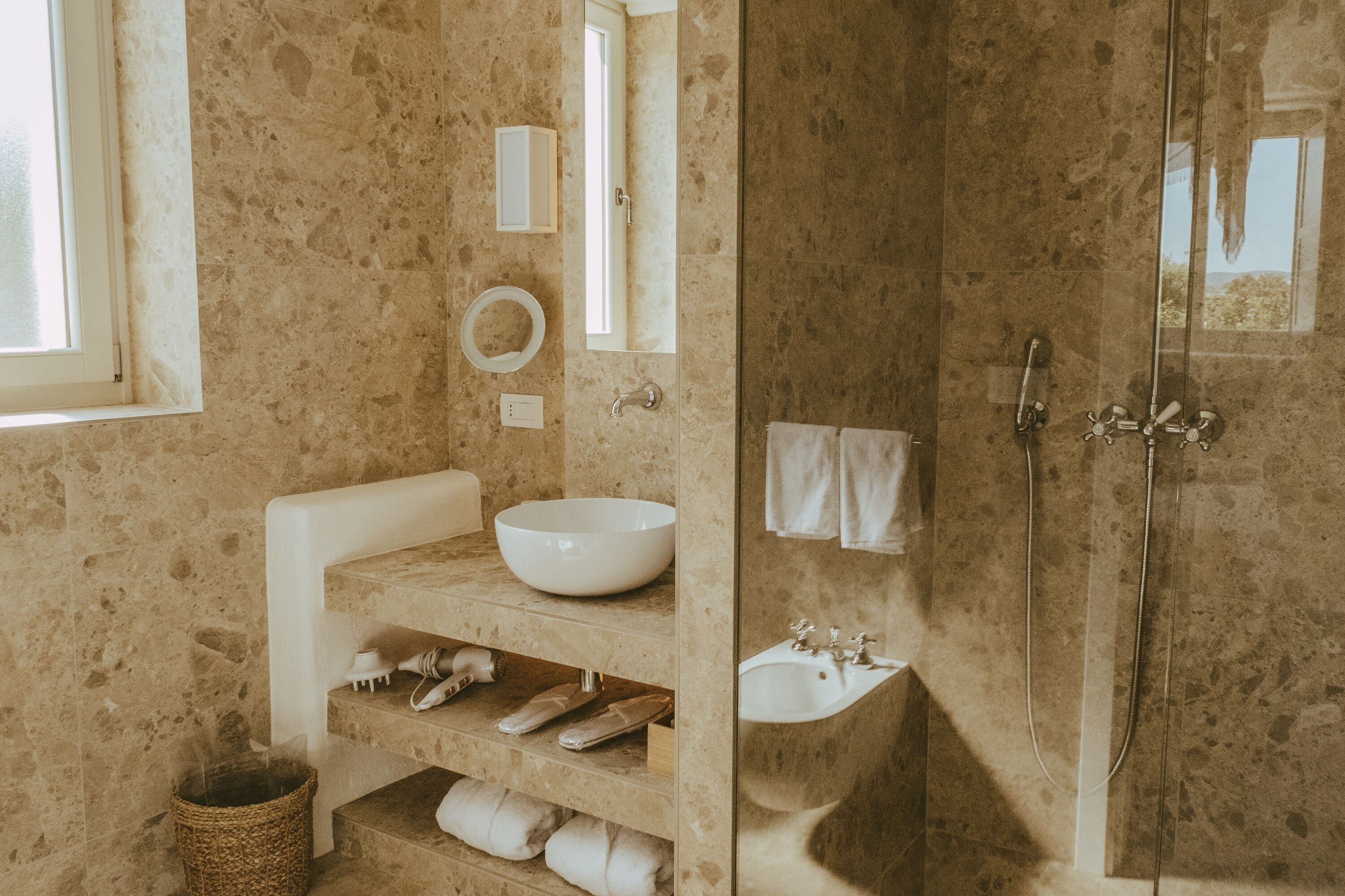 A bathroom with a large mirror, a sink, a shower, and a towel rack.
