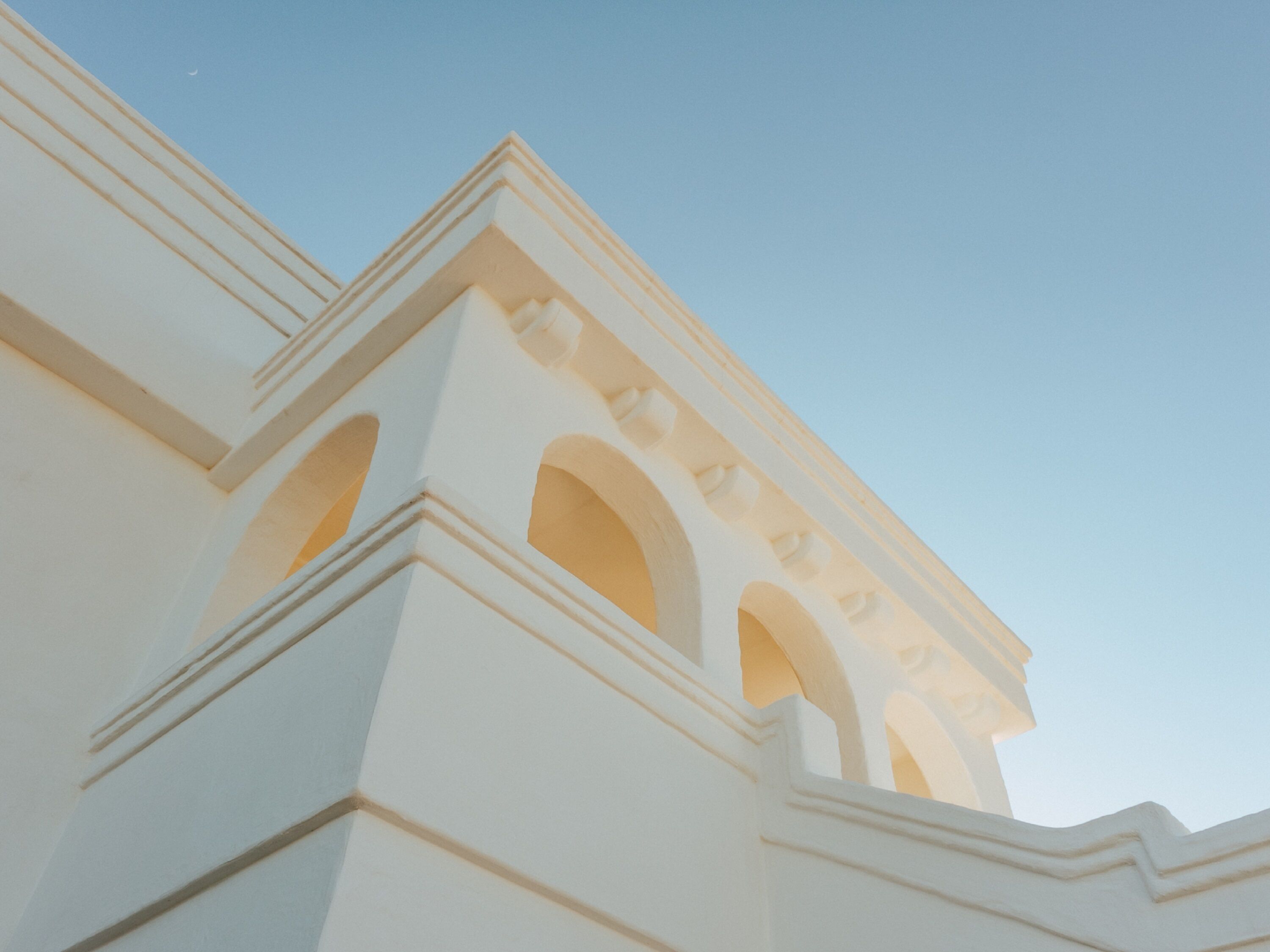 A white building with multiple arched windows and a clear sky.