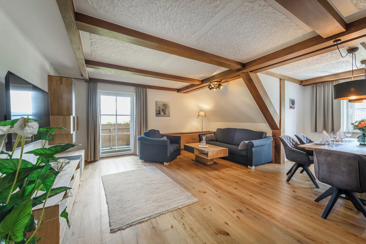 Ein geräumiges Wohnzimmer mit Holzboden, einer Couch, einem Couchtisch und einem Essbereich mit Stühlen und einem Tisch.