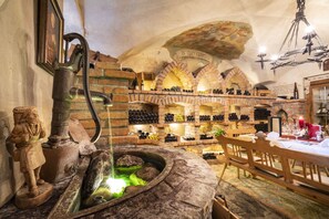 A wine cellar with brick arches, wooden barrels, and a stone fountain. - Hotel & Restaurant Wastlwirt (Sankt Michael im Lungau)