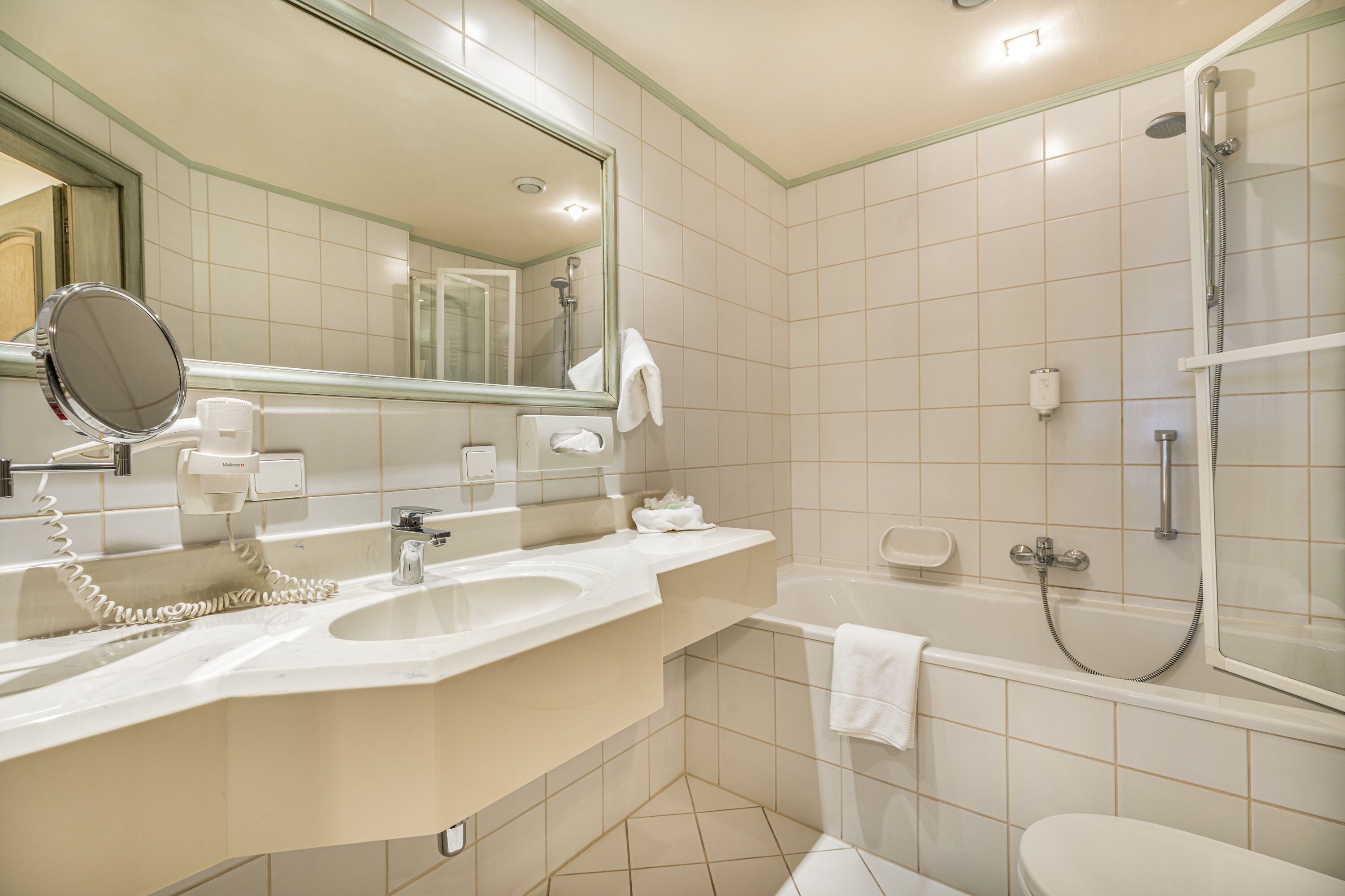 A modern bathroom with a sink, mirror, and a shower area.
