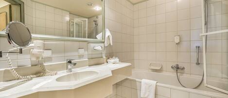 A modern bathroom with a sink, mirror, and a shower area.