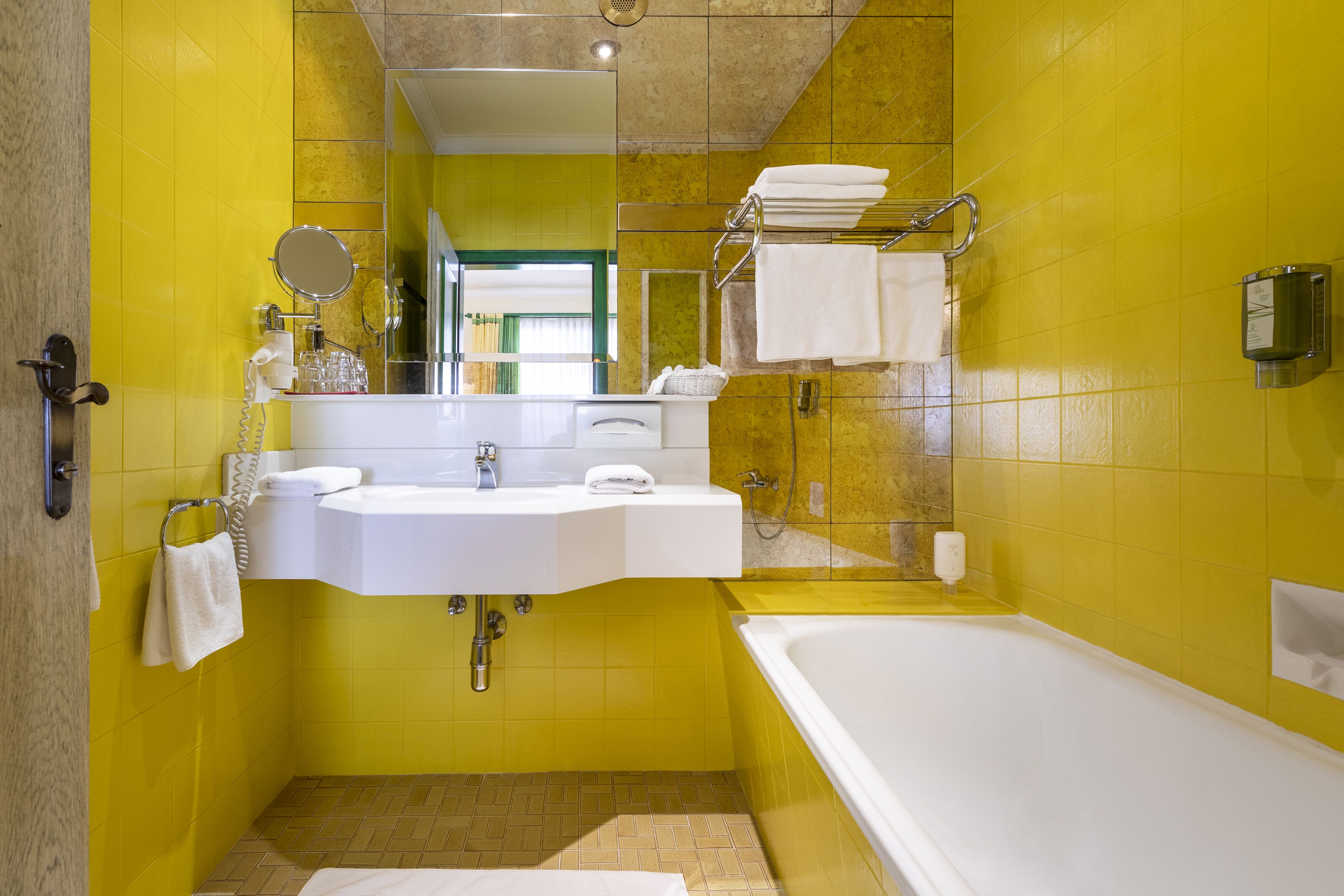 Un baño con paredes amarillas, un lavabo blanco, un espejo y una bañera.