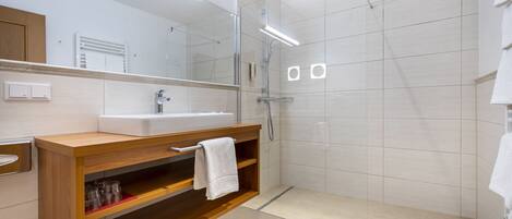A modern bathroom with a glass-enclosed shower, a wooden vanity, and a large mirror.