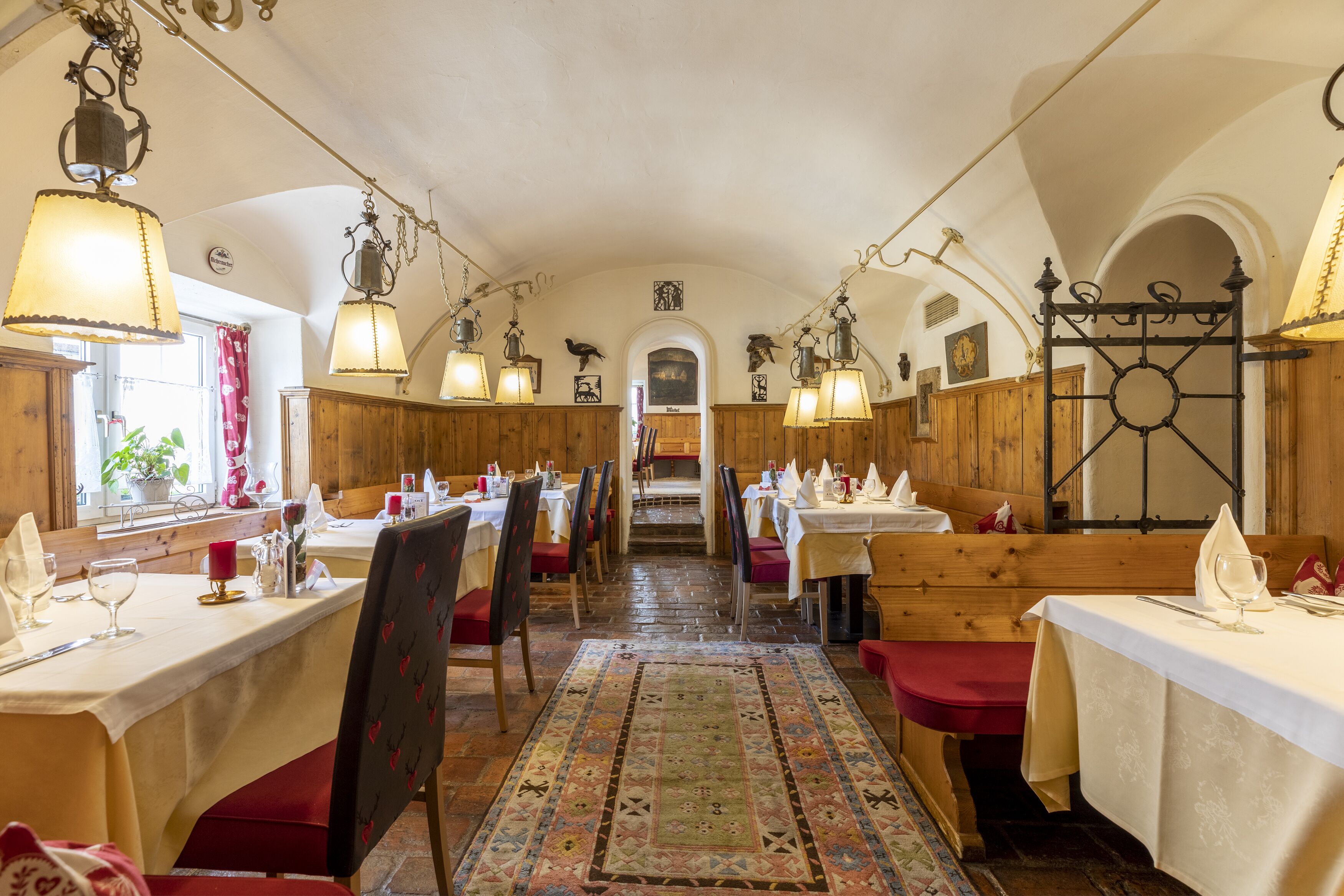 Un restaurant au décor intérieur en bois, avec des tables recouvertes de nappes blanches et des lampes suspendues.