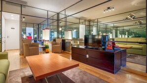 Un salon moderne avec une table basse en bois, un téléviseur posé sur un meuble et un canapé vert.