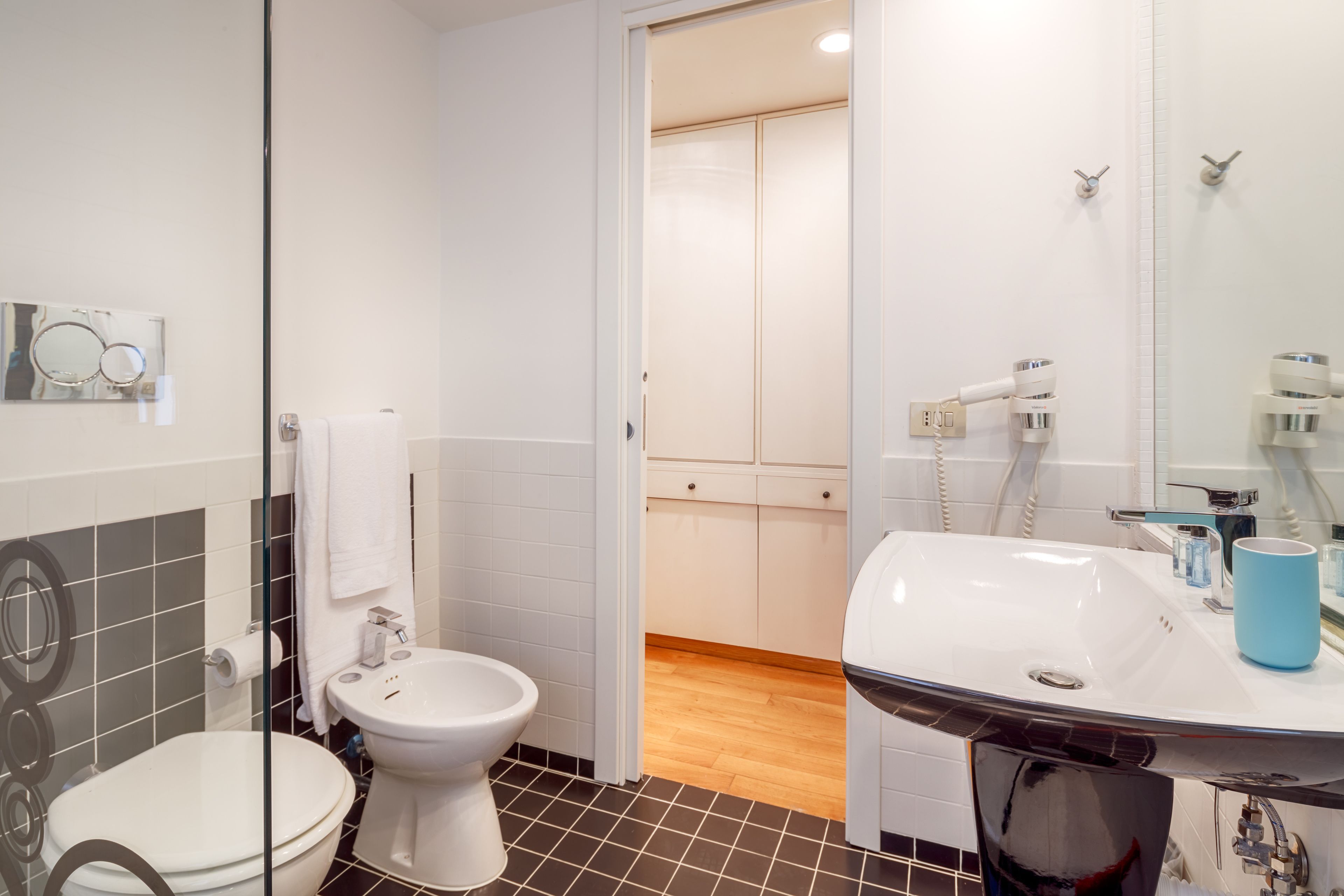 Une salle de bain moderne équipée de toilettes, d’un bidet et d’un lavabo avec un miroir.
