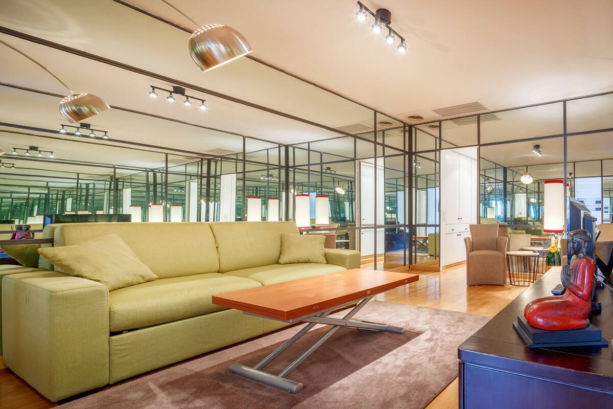 A modern living room with a green sofa, a wooden coffee table, and a red sculpture.