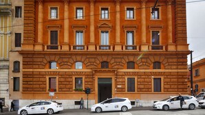 Un bâtiment historique à la façade symétrique, doté de grandes fenêtres et d’une entrée centrale.