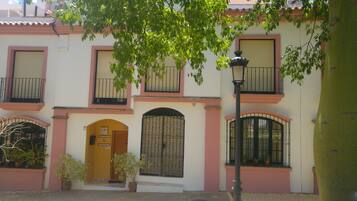 Un edificio con puerta de entrada amarilla, varias ventanas con rejas metálicas y balcones con barandillas negras.