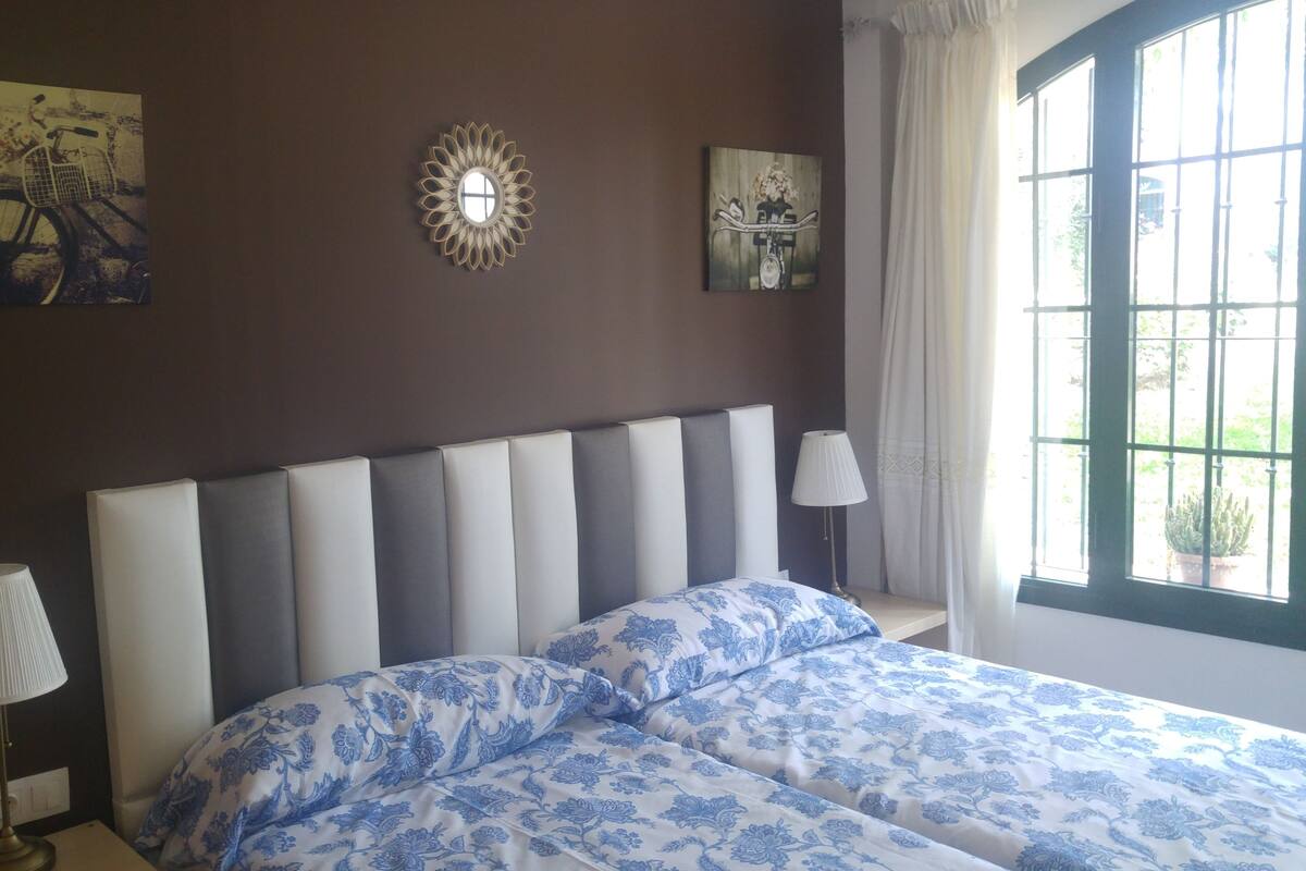 A bedroom with a large bed, two bedside lamps, and artwork on the walls.