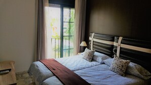 A bedroom with two beds, a window with curtains, a bedside lamp, and a wooden headboard. - Hospederia V Centenario (Estepona)