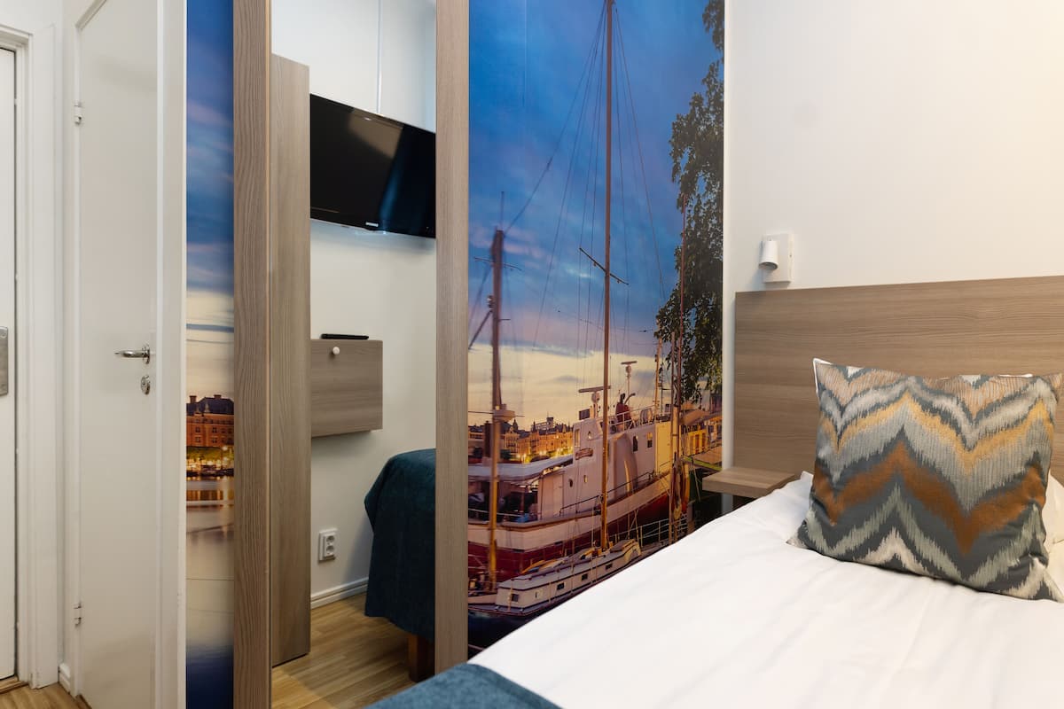 Habitación de hotel con cama, televisor montado en la pared y un amplio ventanal con vista a la ciudad.