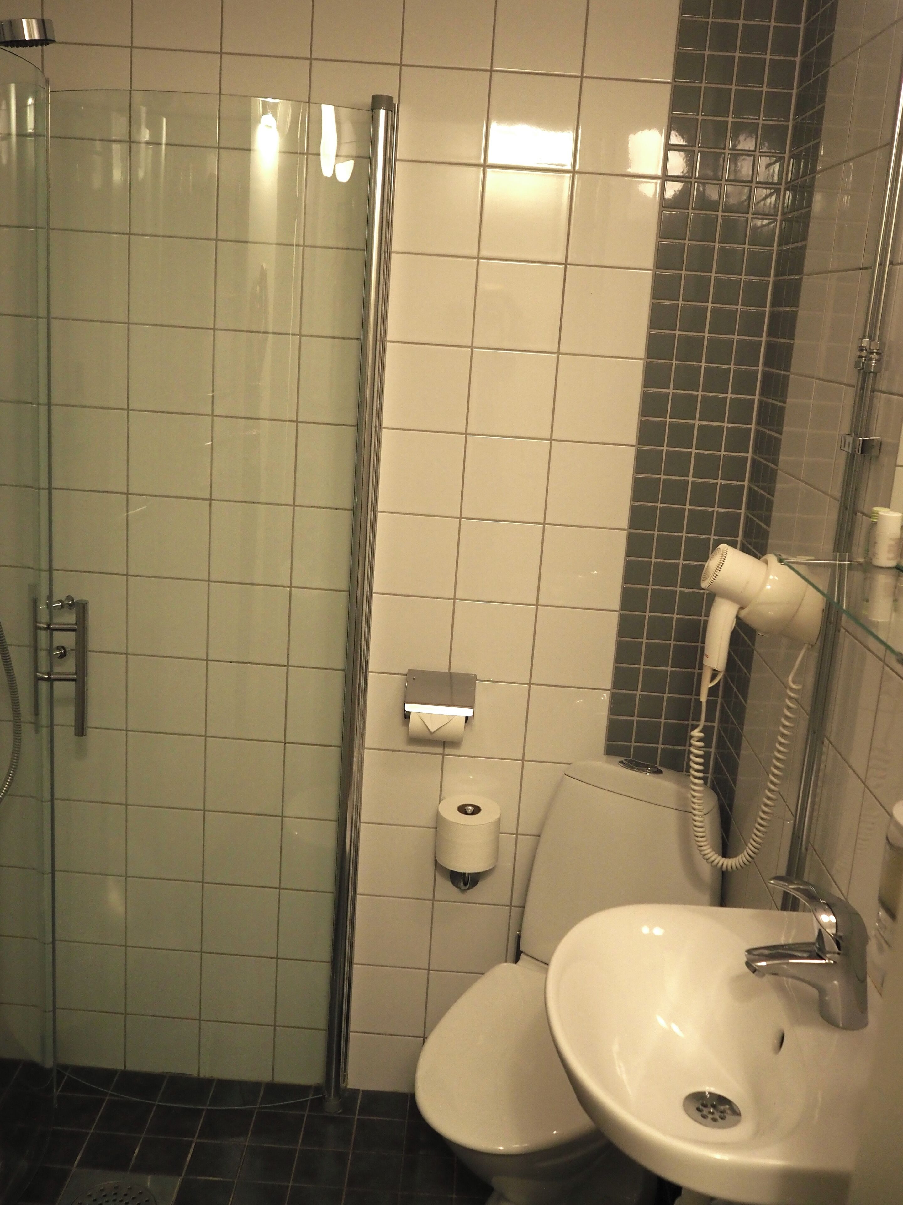 Un baño con cabina de ducha de vidrio, inodoro y lavabo.