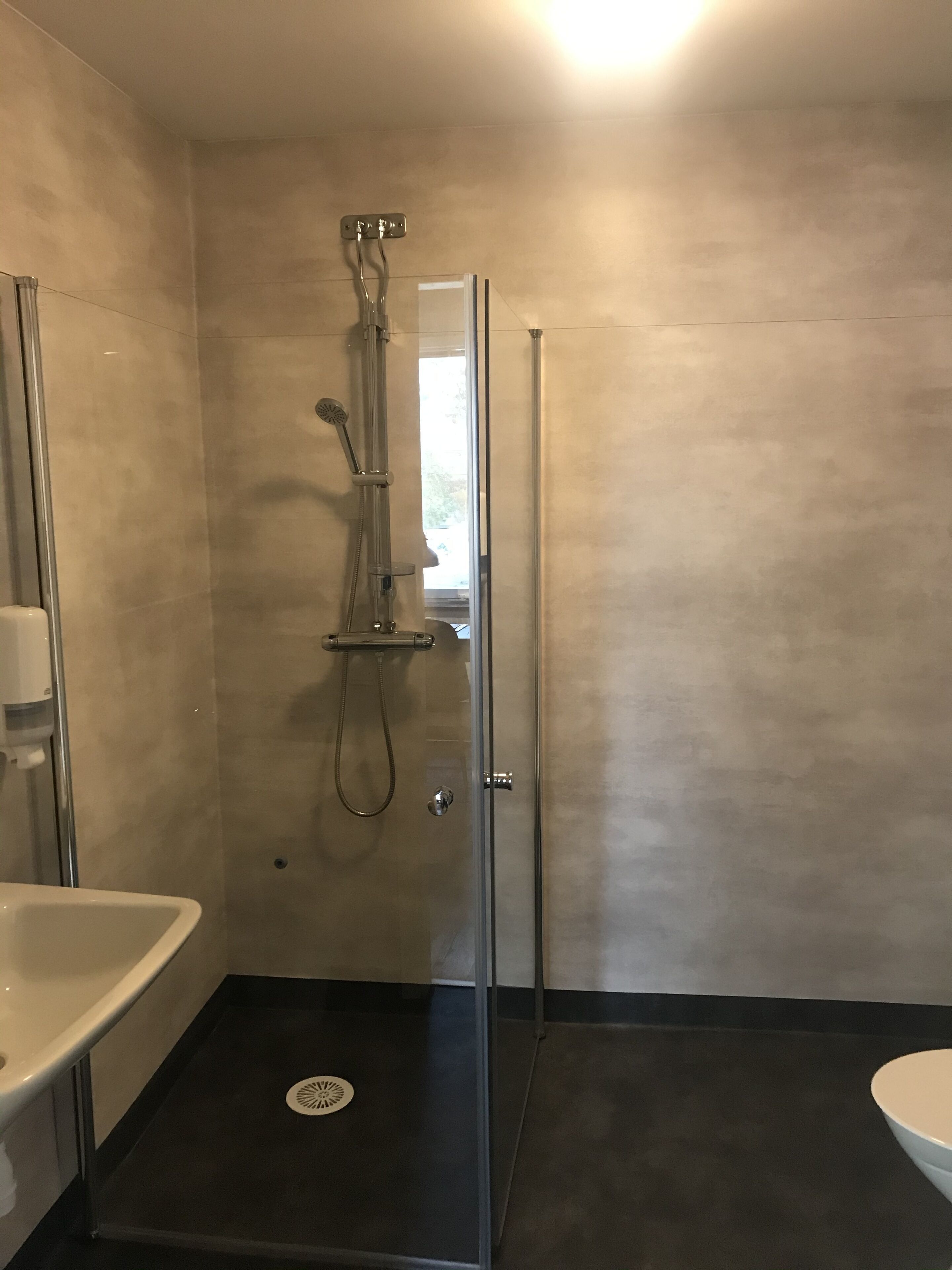 A modern bathroom with a glass-enclosed shower, a white sink, and a toilet.