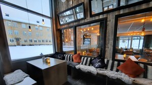 A cozy seating area with a bench and a table, large windows offering a view of the outside.