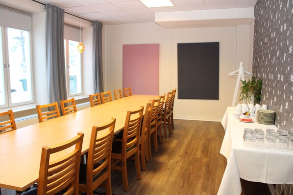 A conference room with a long wooden table, multiple chairs, a projector screen, and a table with glassware and plates. - Sidsjö Hotell & Konferens (Sundsvall)