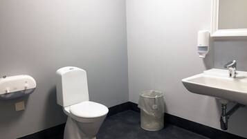 A small bathroom with a toilet, a sink, and a hand sanitizer dispenser.