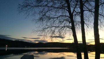 A calm lake at dusk with a wooden dock extending into the water.