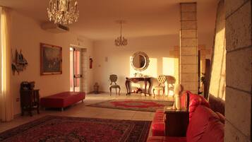 Ein geräumiges Wohnzimmer mit einem roten Sofa, einem Chandelier und einem großen Spiegel.