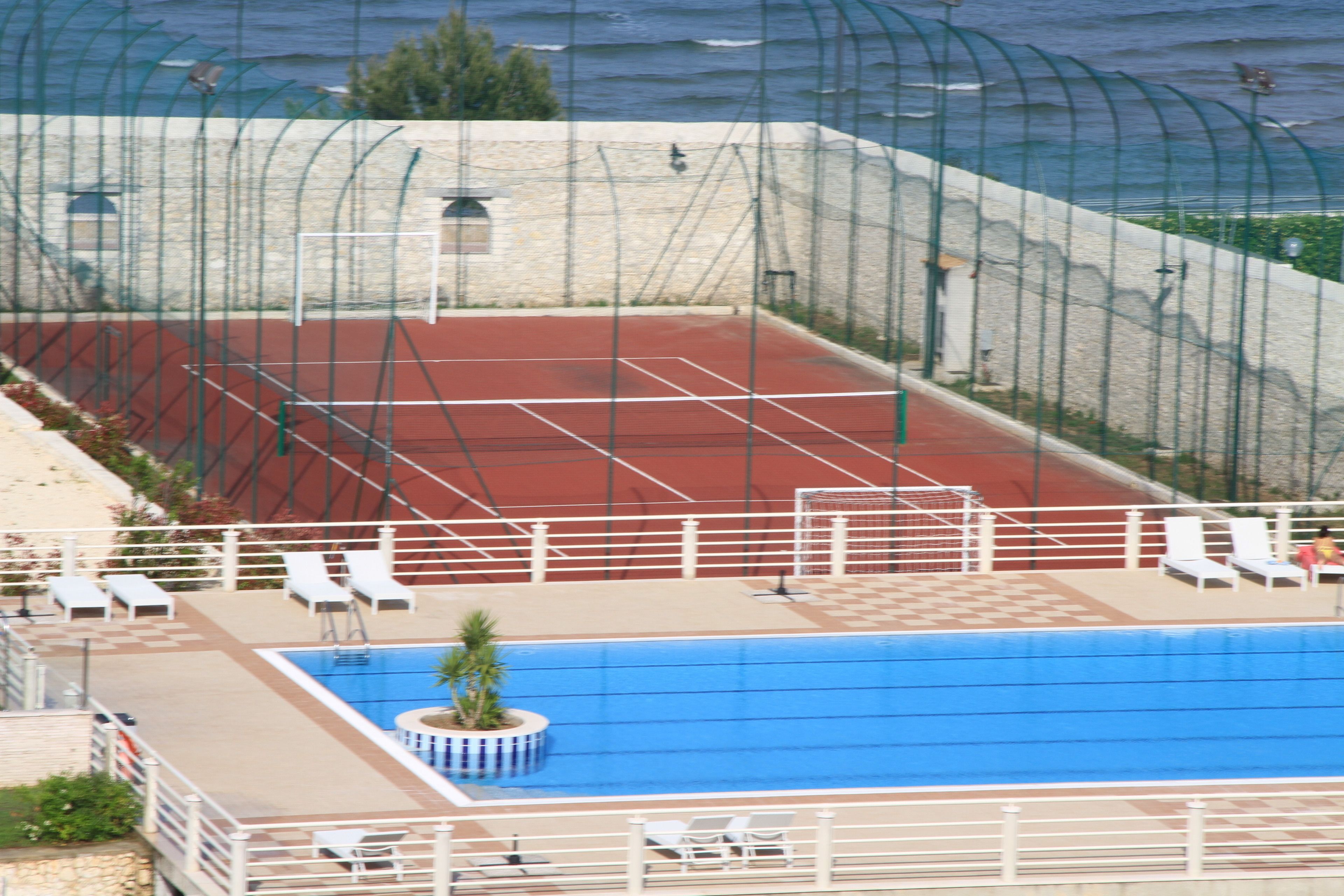 A swimming pool with a red track and white lounge chairs.