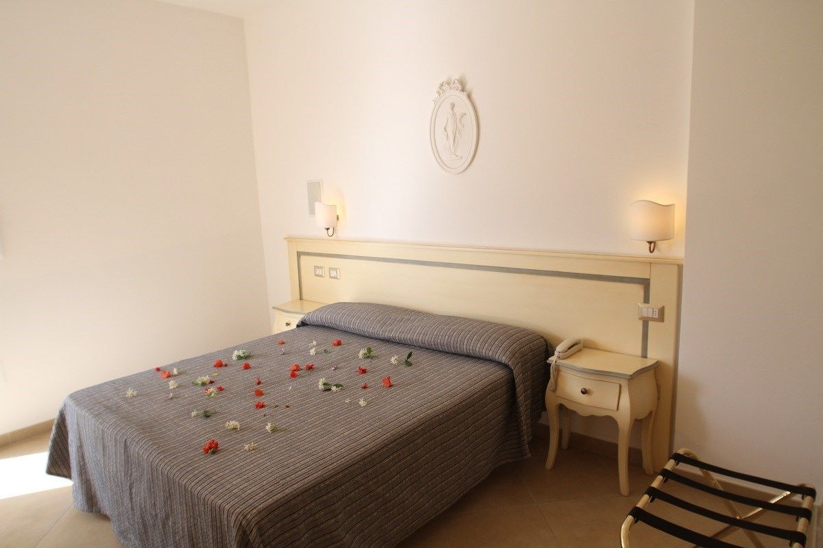 A bedroom with a bed, bedside table, lamp, and a wall-mounted decoration.