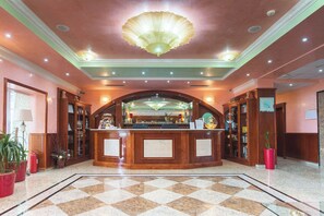 A lobby with a checkered floor, a reception desk, and a large chandelier.