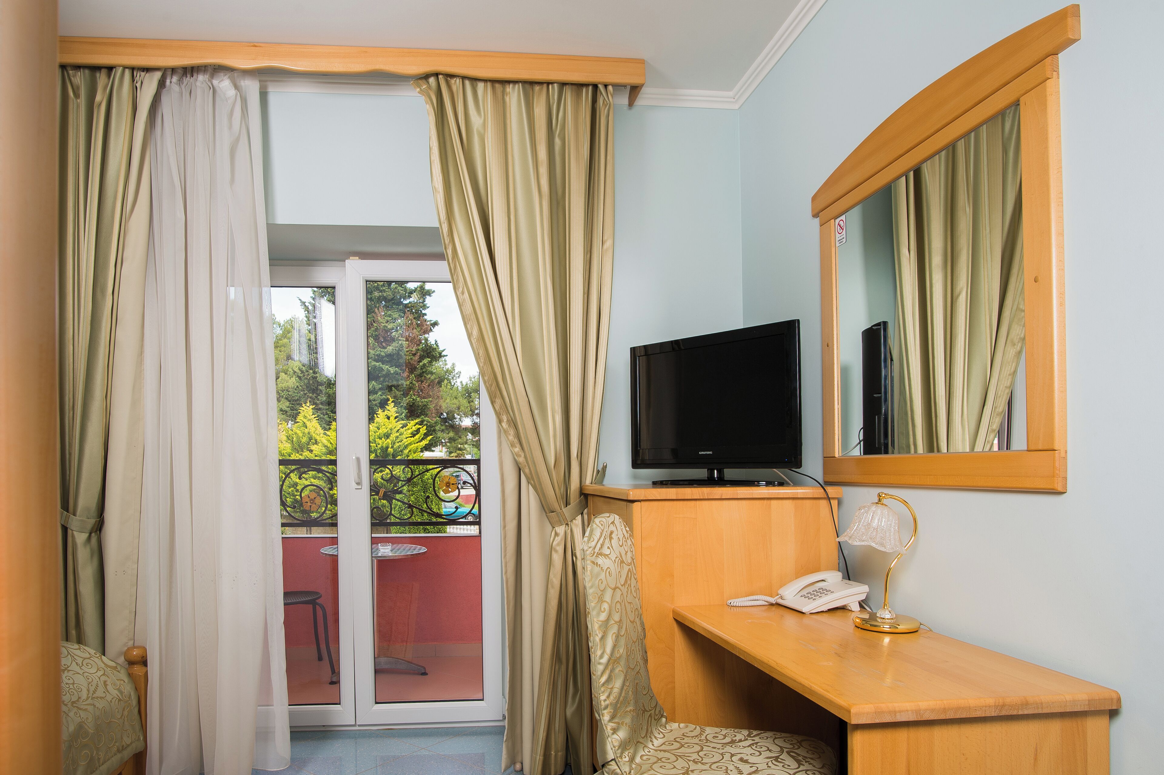 Une chambre équipée d’une télévision, d’un bureau avec une lampe, d’un téléphone et d’un miroir.