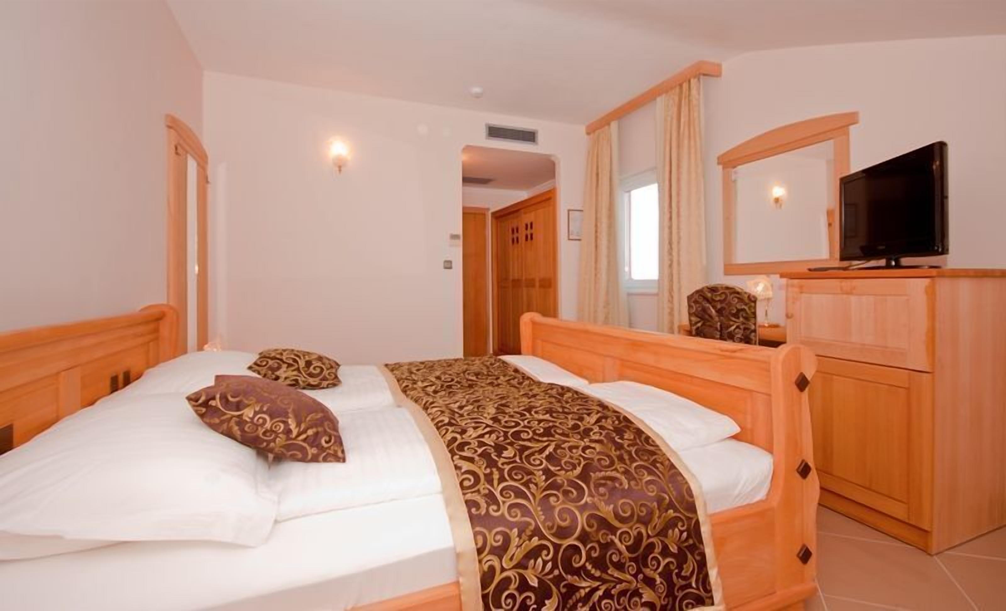 A bedroom with a wooden bed, a television, and a wardrobe.