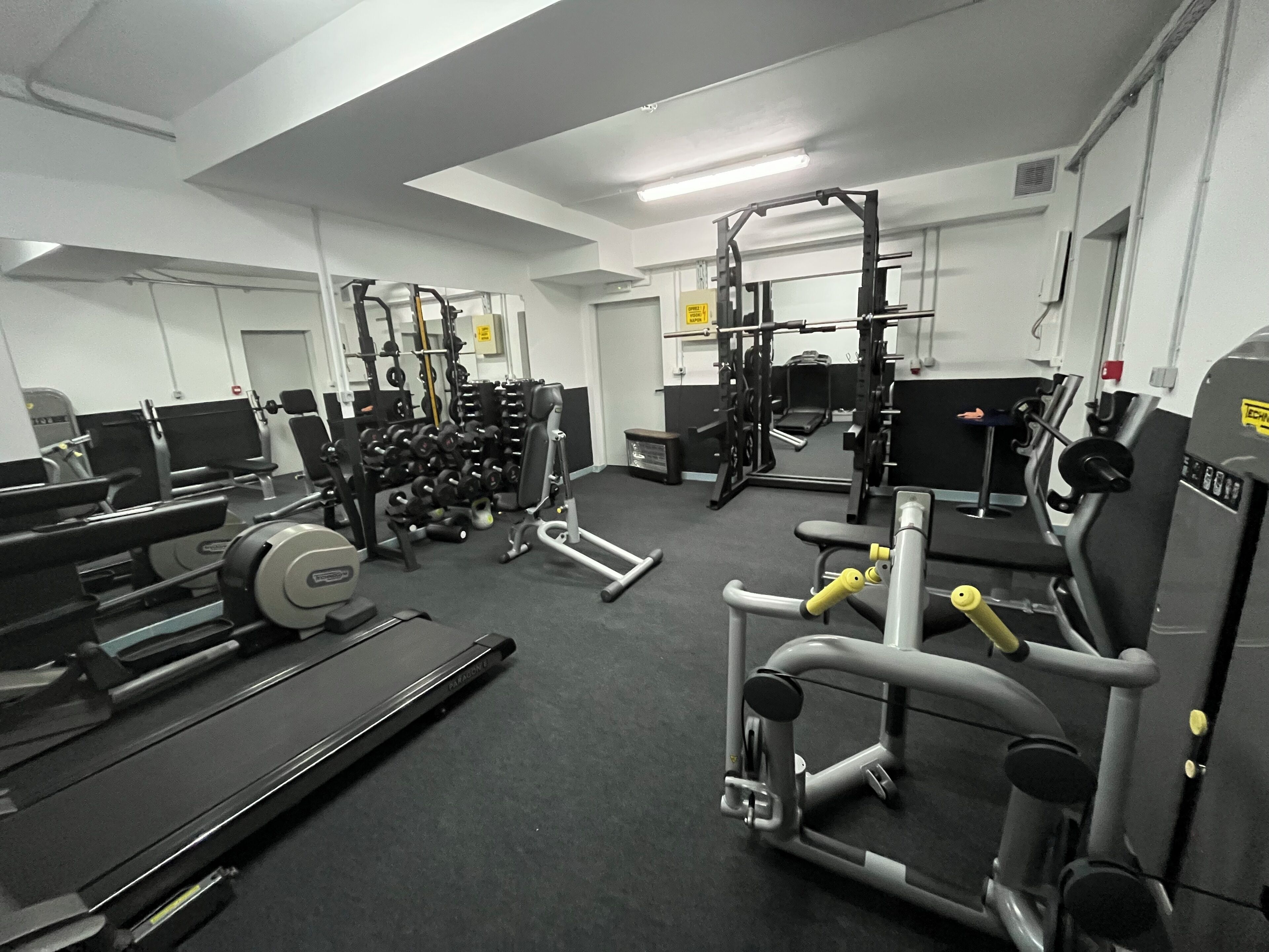A gym with various exercise equipment including treadmills, weight machines, and free weights.