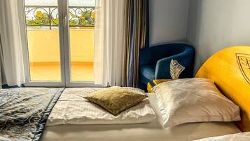 A hotel room with two beds, a view of the sea, and a balcony with a railing.