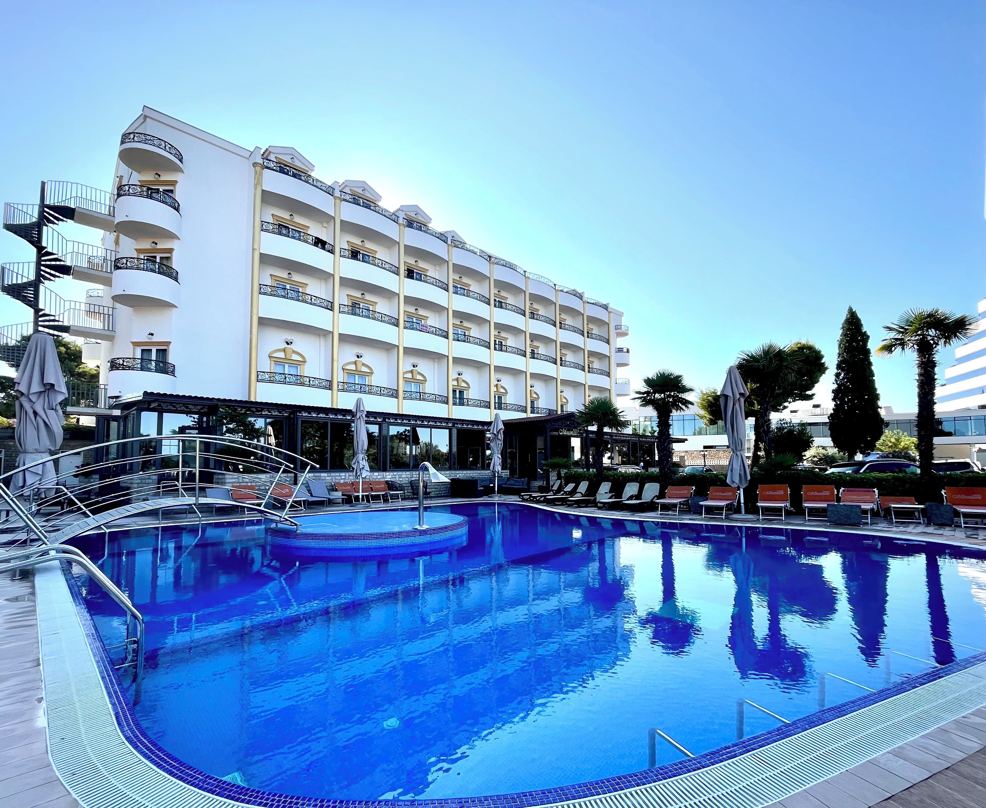 A hotel with a swimming pool, multiple balconies, and outdoor seating areas.