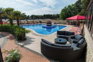 A pool area with a hot tub, lounge chairs, and outdoor seating.