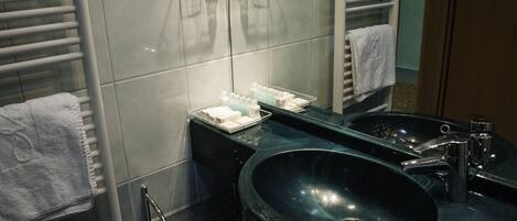 Een moderne badkamer met twee wasbakken, een grote spiegel en een handdoekhouder.