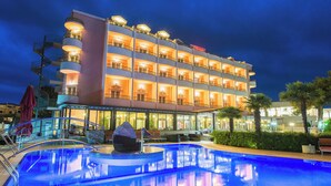 A hotel with multiple balconies, a swimming pool, and outdoor seating areas. - Hotel Miramare (Vodice)