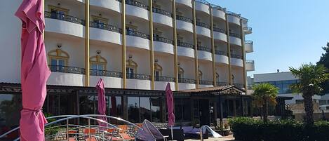 Ett hotell med en swimmingpool, utomhusplats med sittmöbler och en flervåningsbyggnad med balkonger.