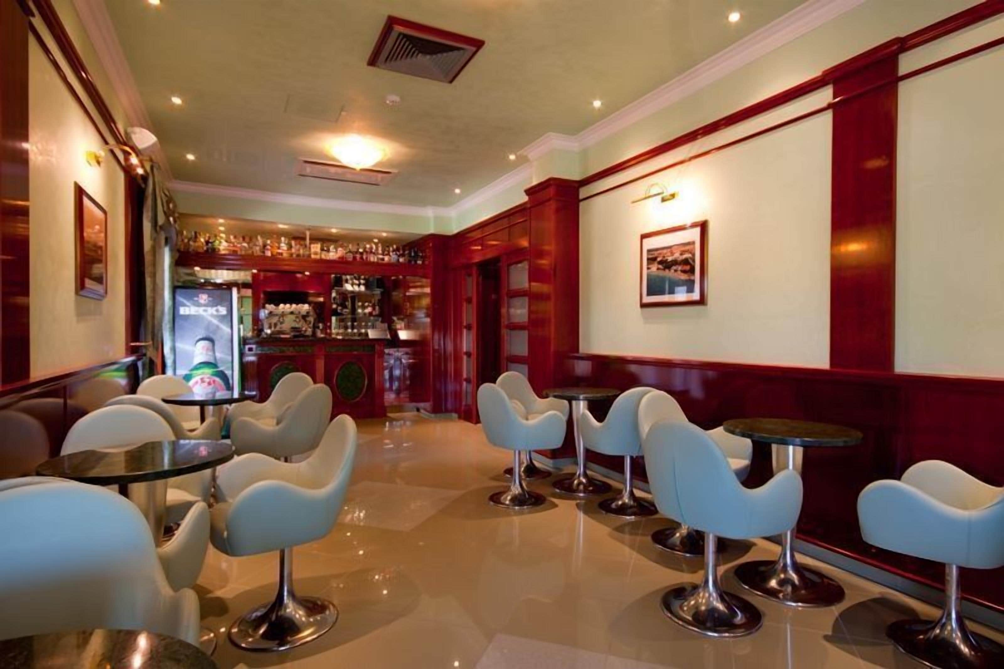 Een bar met witte barkrukken en een bar.