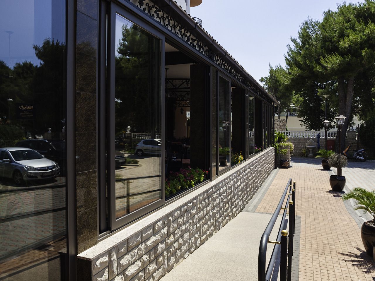 A building with large glass windows, a stone base, and a metal railing along the sidewalk.