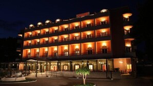 A multi-story hotel with a central courtyard, balconies on each floor, and a well-lit entrance. - Hotel Miramare (Vodice)