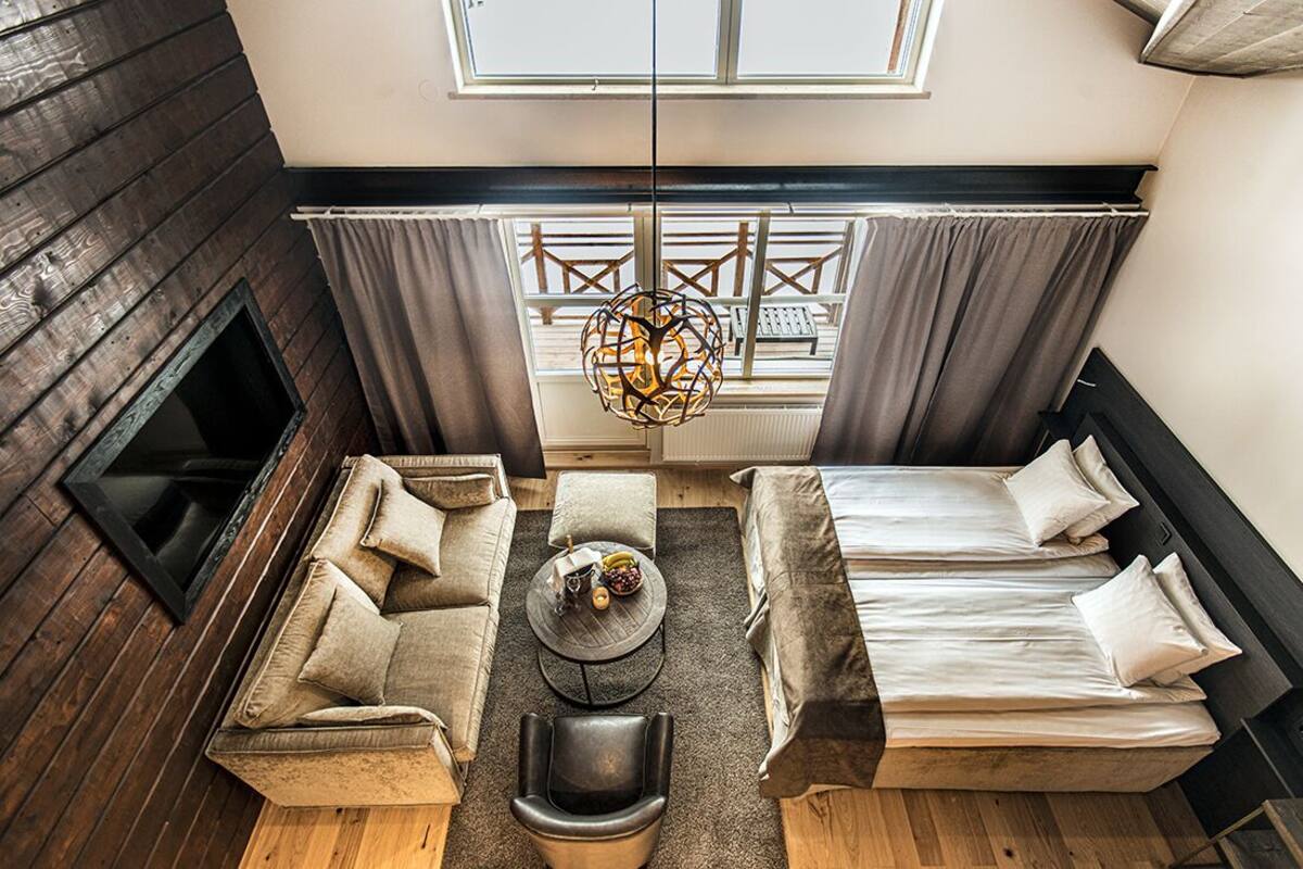 A modern room with a sofa, a chair, a bed, and a fireplace.