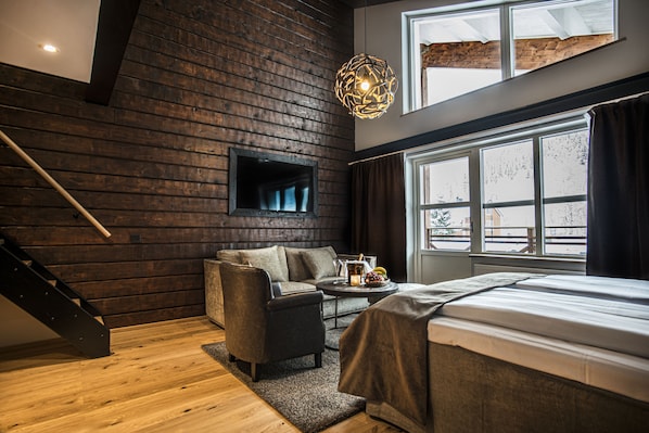 Ein modernes Schlafzimmer mit einer Holzwand, einem Sofa, einem Bett und einem großen Fenster.