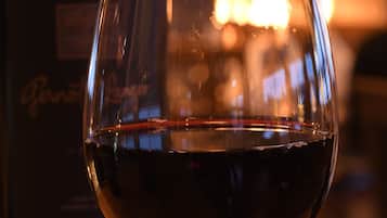 A glass of red wine with a bottle in the background.