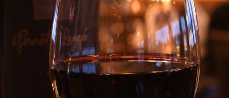 A glass of red wine with a bottle in the background.