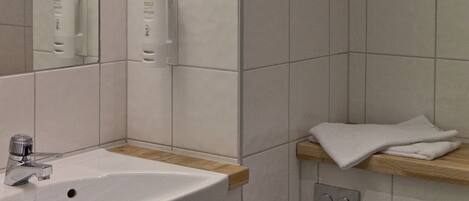 A bathroom with a white sink, mirror, and towel rack.
