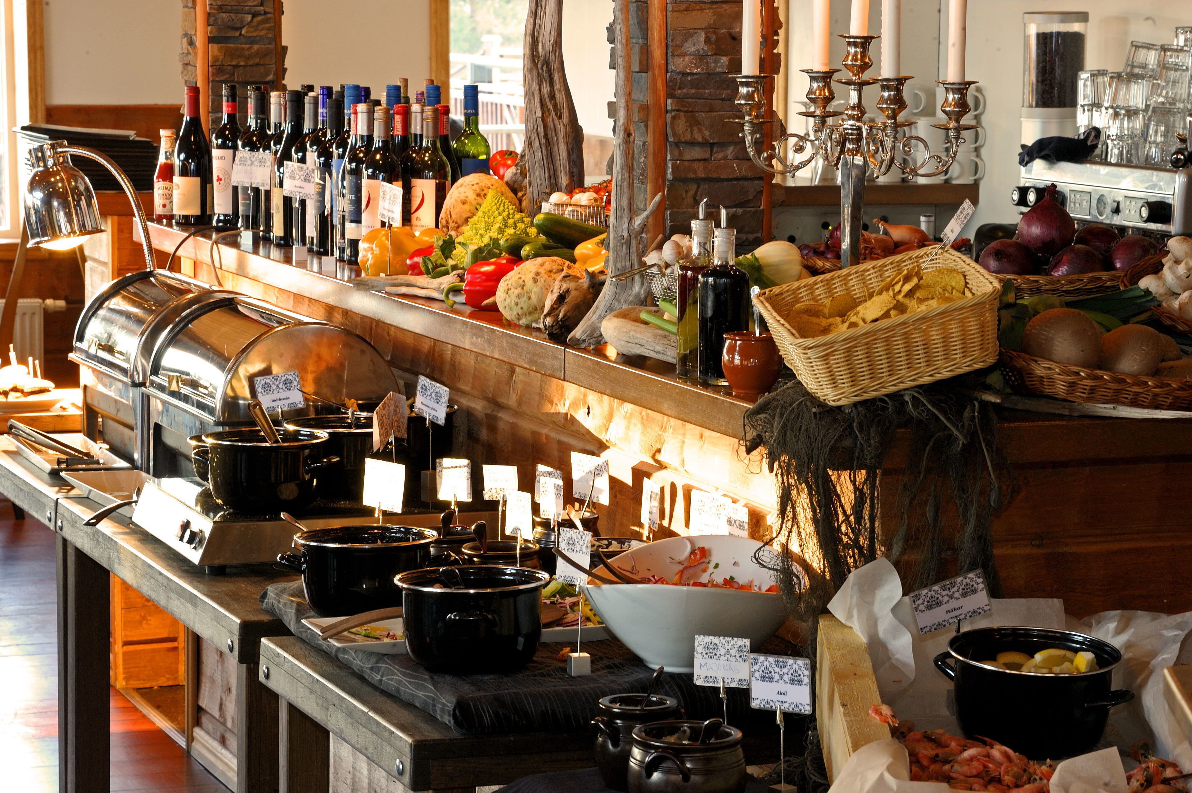 Un bufé con diversos alimentos, utensilios de cocina y una selección de botellas de vino.