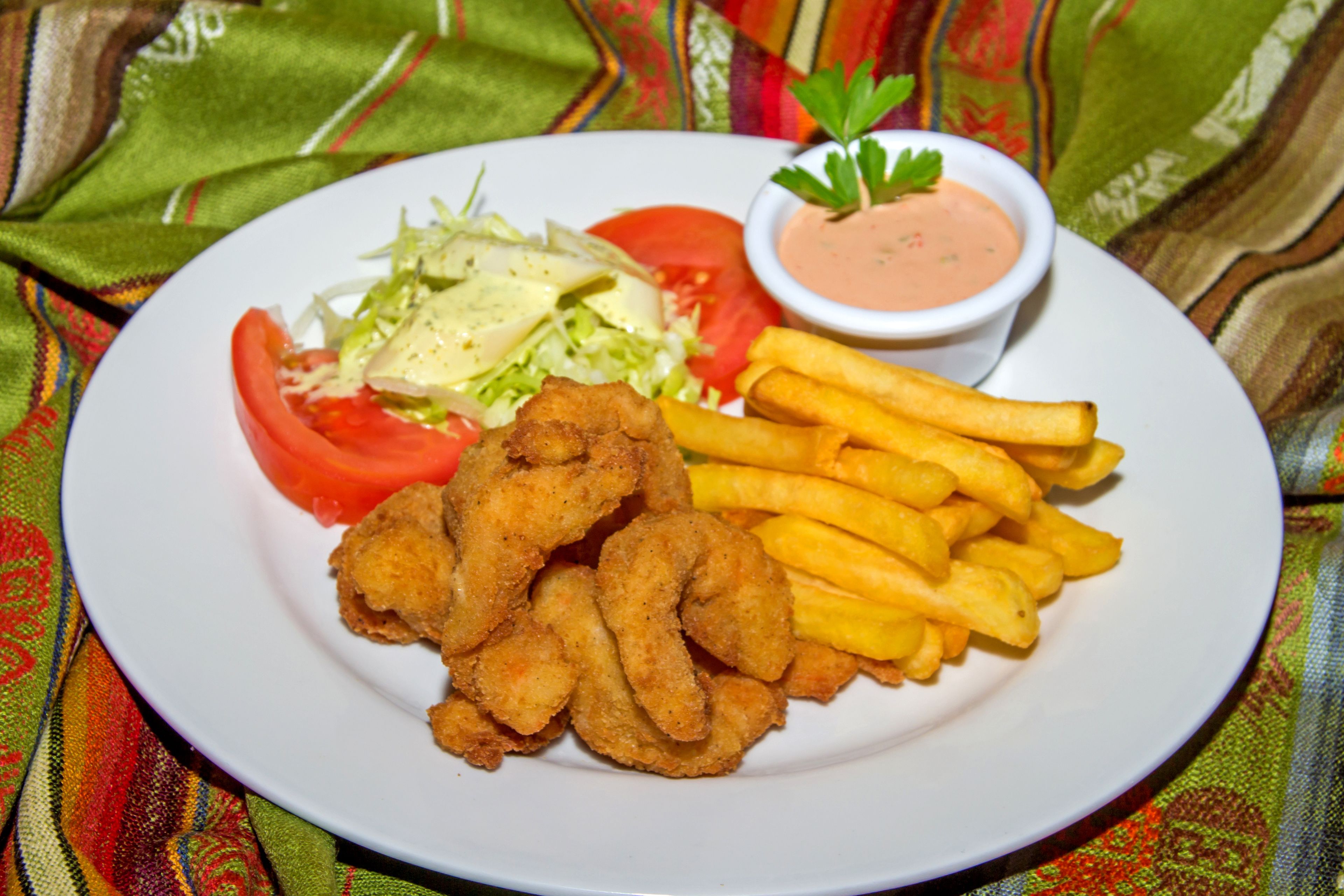 A plate of food including fried items, French fries, a salad, and a small bowl of sauce.