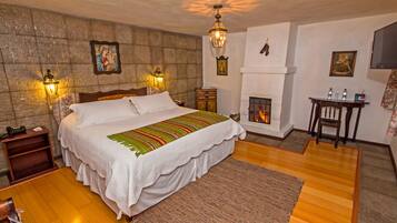 A well-appointed bedroom with a large bed, a fireplace, and a nightstand with a lamp.