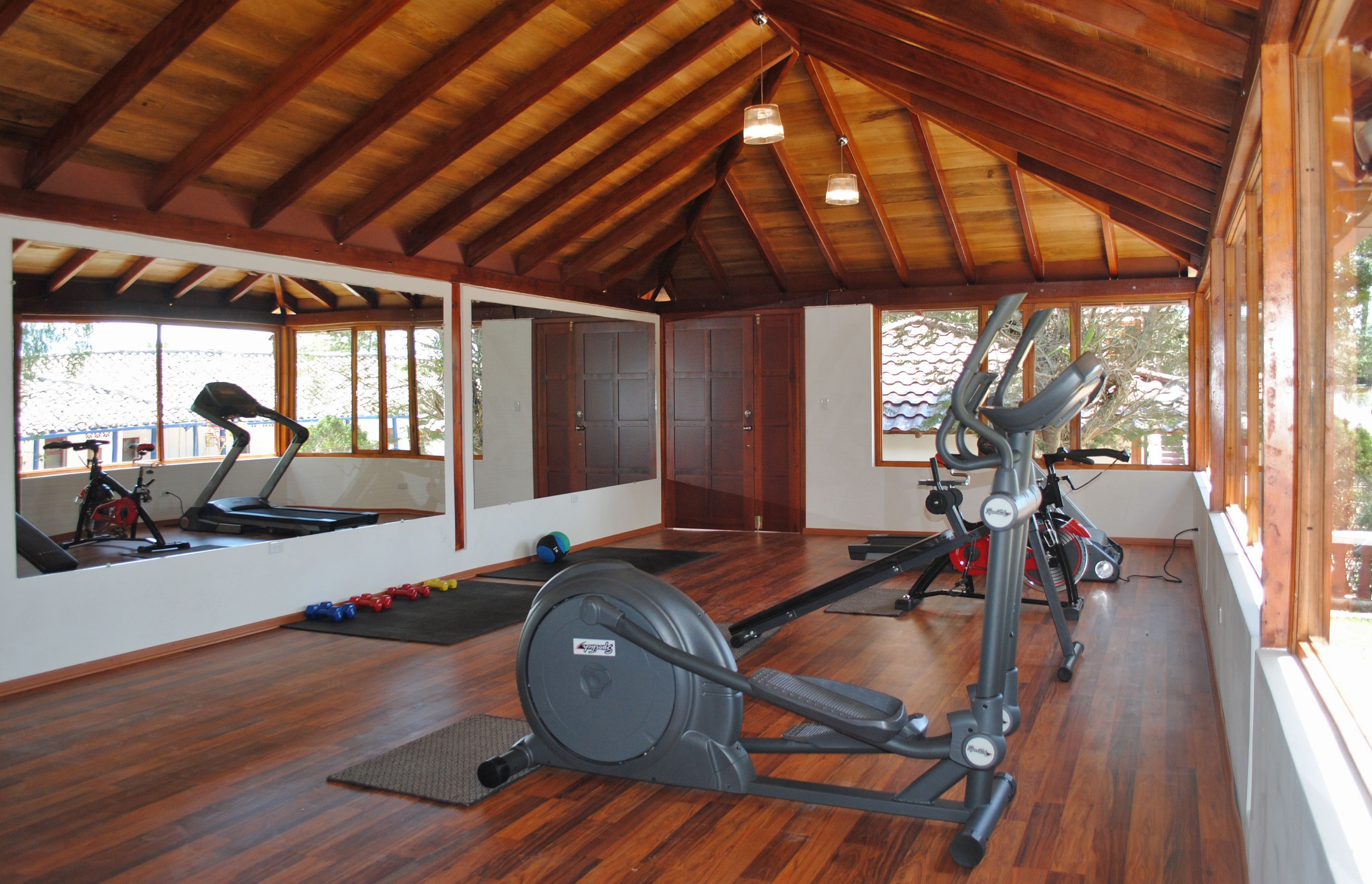A gym with exercise equipment, wooden floors, and large windows.