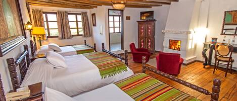 Une chambre traditionnelle avec deux lits, une cheminée et un fauteuil rouge.